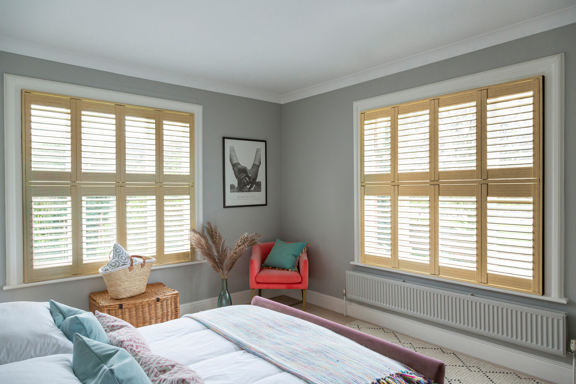 Honey oak light brown shutters fitted to two windows in a grey decorated bedroom