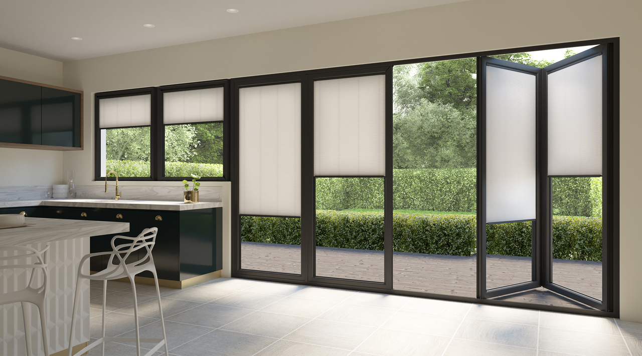 White coloured blinds fitted to bi fold doors in a kitchen with white flooring, navy kitchen cabinets and white dining table