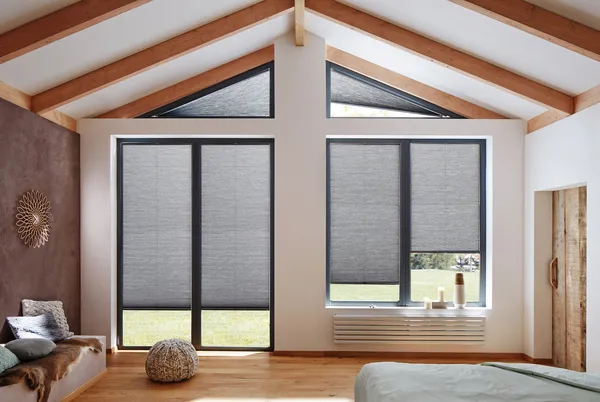 Room with brown wall and bench seating with cushions to left, wooden floor and gable end windows and doors dressed in charcoal duette blinds.