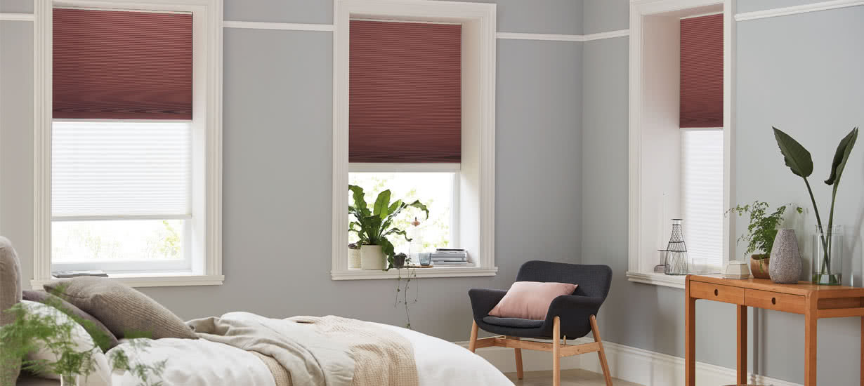 Red blinds fitted to rectangular windows in a bedroom
