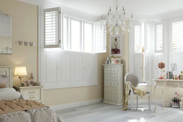 French-chic bedroom in white/primrose, windows with white tier on tier shutters, top partially open, lower solid closed, chandelier above white painted wood floor, white wooden furniture.