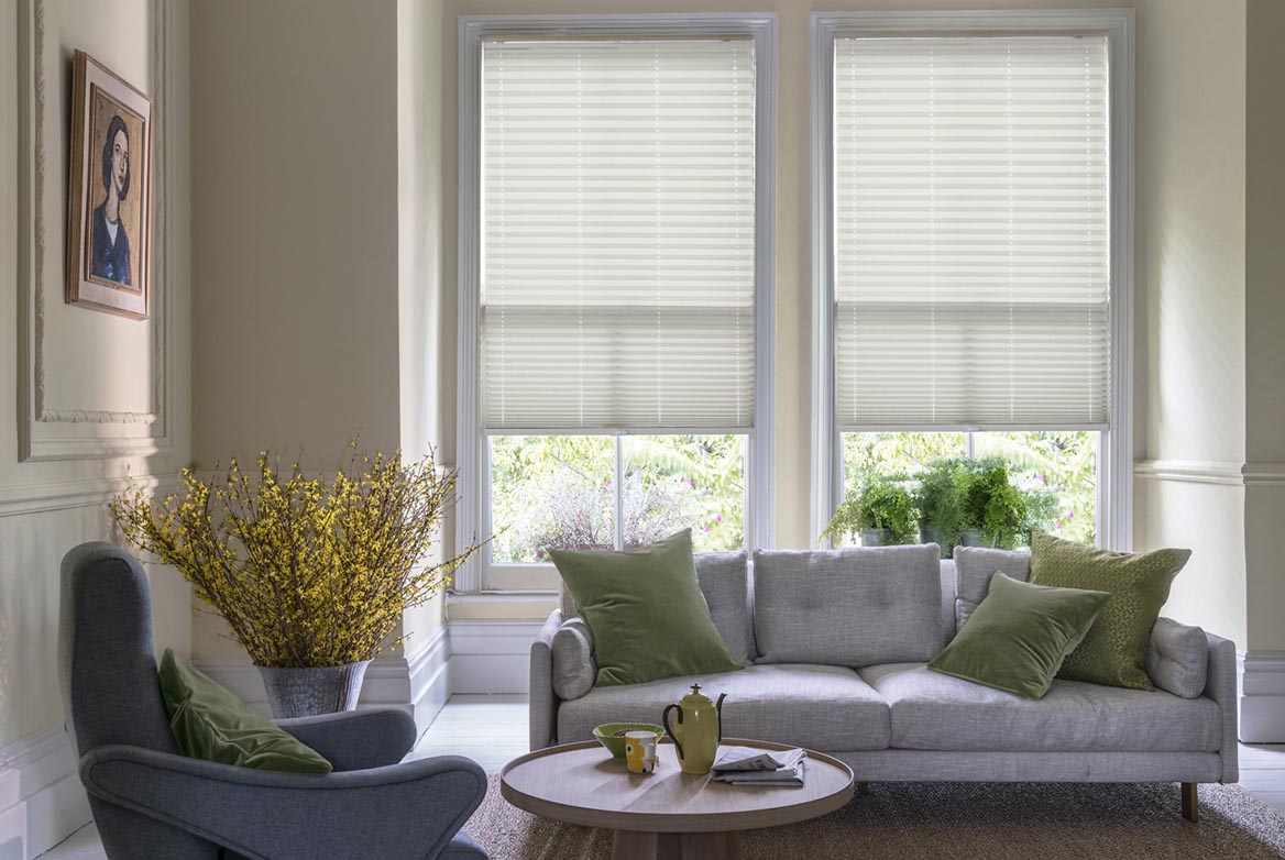 Decorated in a plain style Solartex Chintz Ivory natural Pleated blinds are fitted to windows in a kitchen with marble counter tops and cream coloured fixtures.
