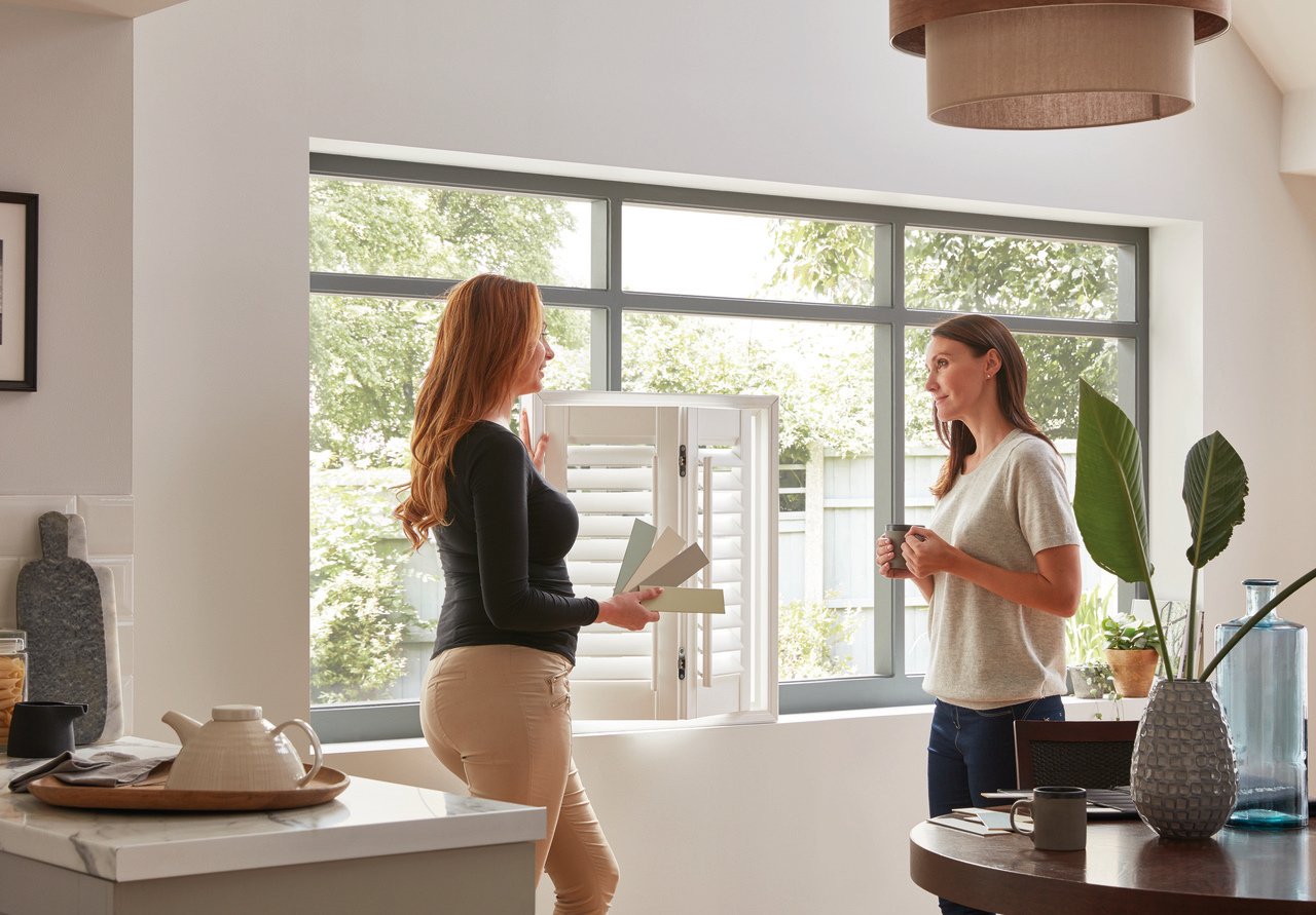 A Thomas Sanderson is showing a shutter to a customer allowing with a variety of different coloured swatches to choose from