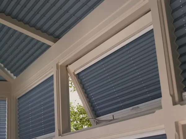 Close up of a transom conservatory window, open, dressed in a deeo azure blue pleated blind within the frame recess.