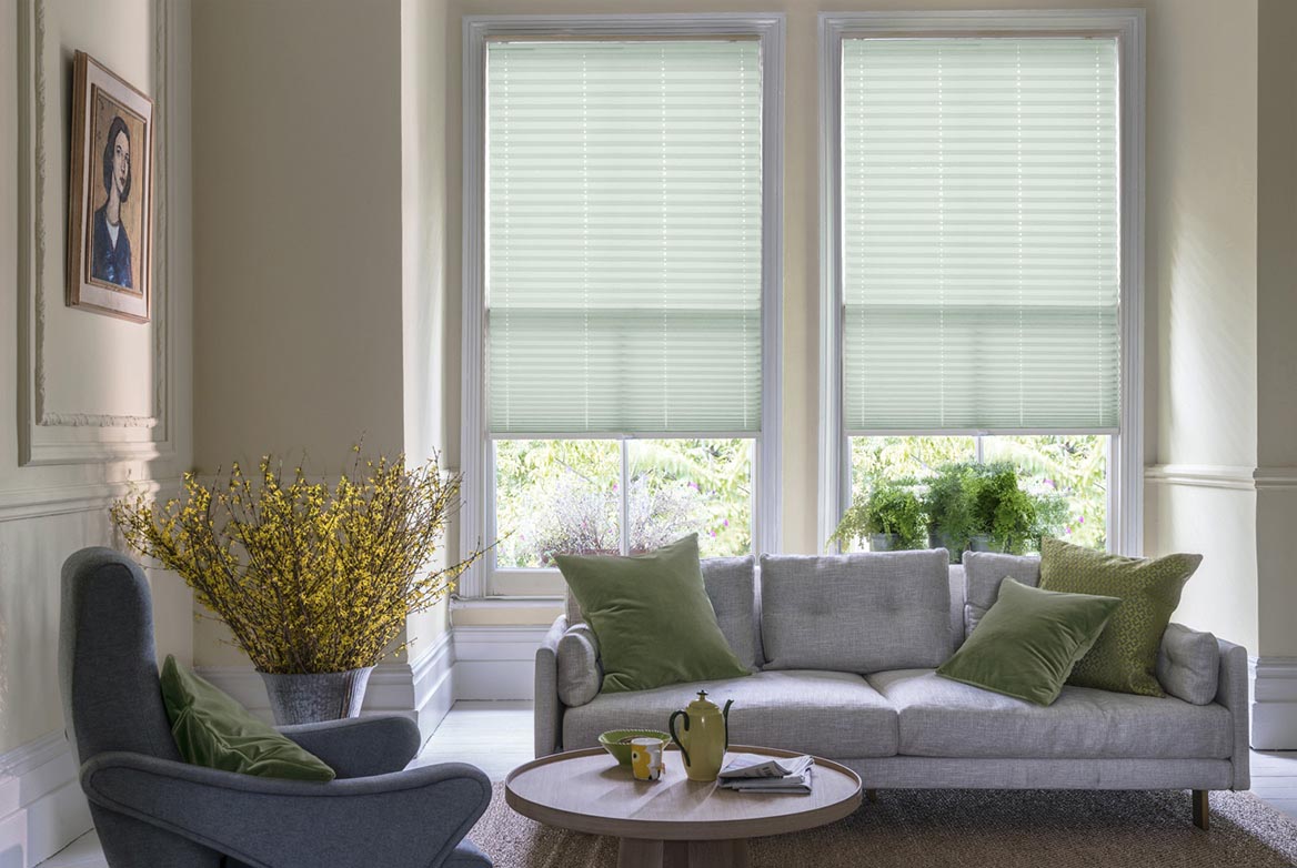 duck egg California Ocean View Pleated blind are fitted to a series of windows in a kitchen decorated with marble counter tops, white walls and drawers. The Pleated blinds are decorated in a plain style.