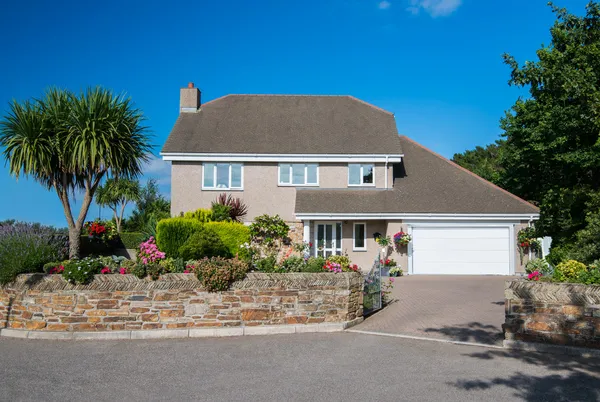 60s-style property in floral setting with dormer integral garage with white sectional garage door and matching front door.
