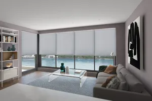 Grey living room with wood parquet floor, grey rugs, brown sofa, and windows and door dressed in light grey duette blinds lowered halfway with views of a pool outside.