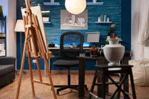 Conservatory with artist easel, desk and chair and windows draped with cream voile curtains. 