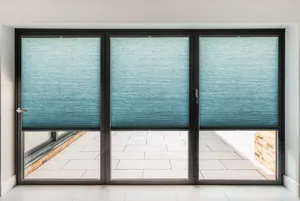 Close in on a set of dark brown bi-fold doors with each of the three doors dressed in marine blue duette blinds fitted into the frame and lowered three quarters.