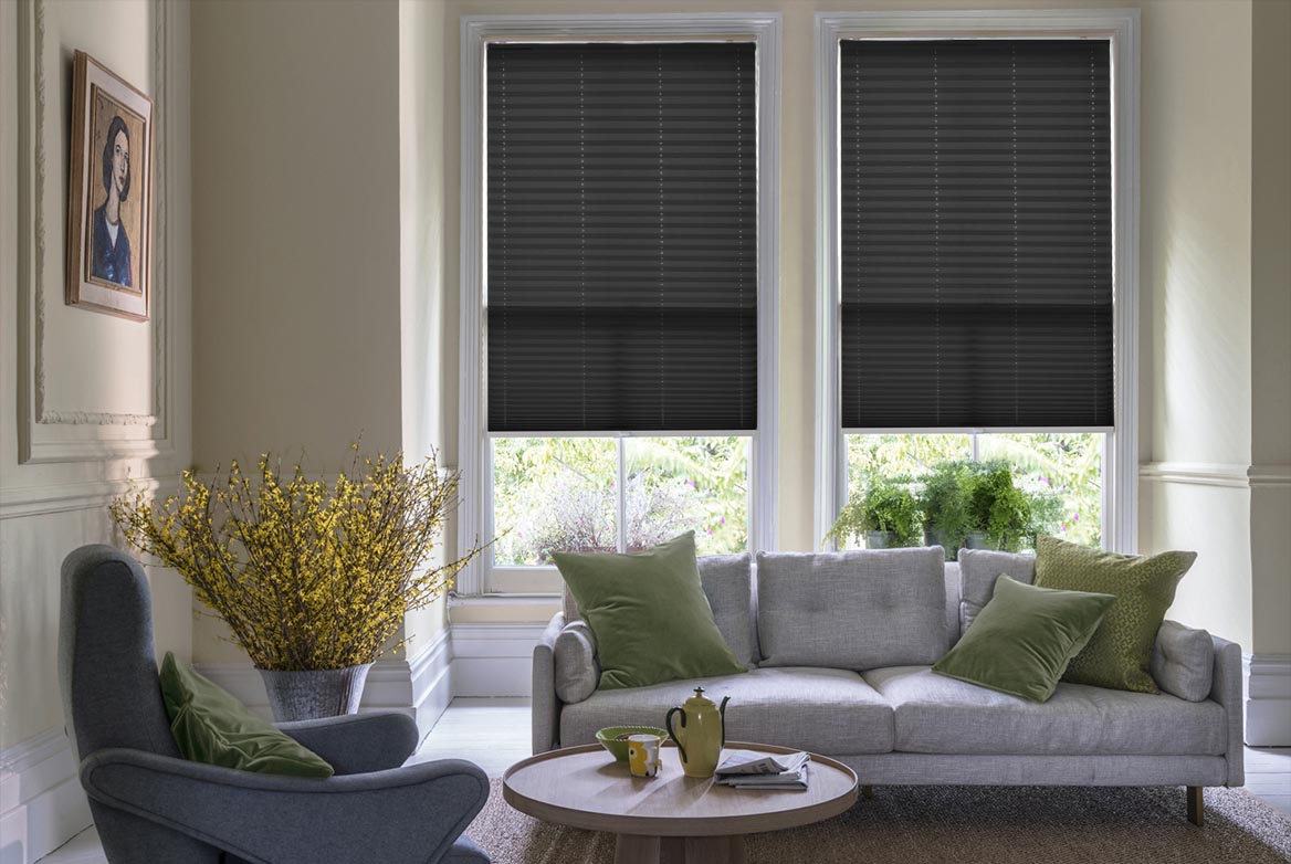 monochrome Pleated blinds have been fitted to multiple windows in a luxuriously styled kitchen in marble and white. Solartex Chintz Noir Crush has a plain style that complements the room.