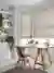 Home office with pale wood floor and large abstract pattern rug, trestle table desk with small angle poise lamp over laptop in front of bay windows dressed in roller blinds with a pale brown swirling pattern.
