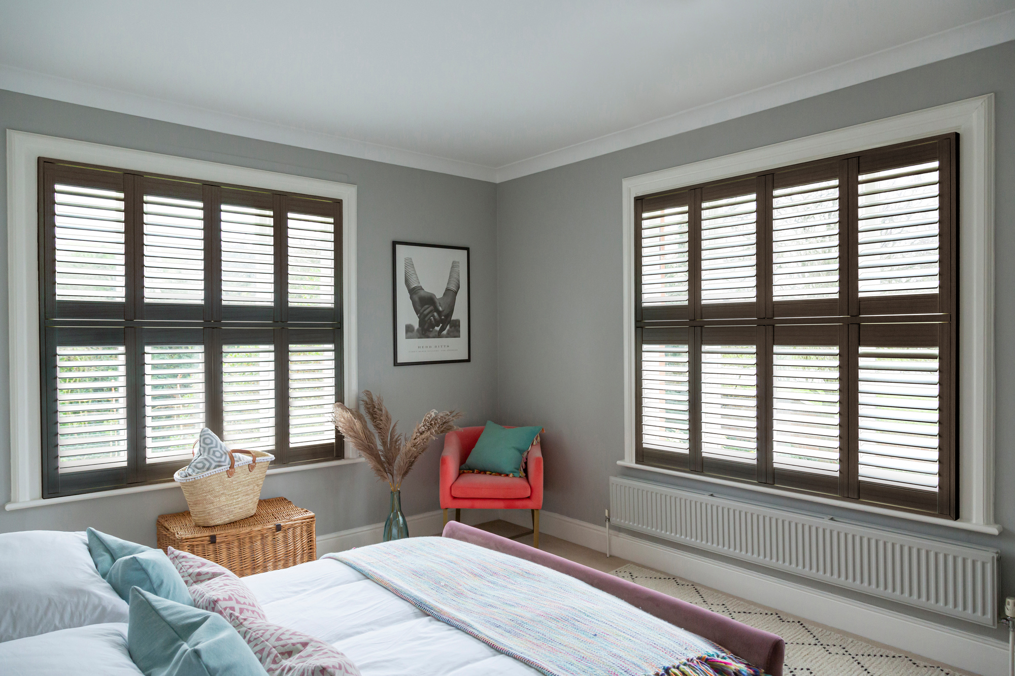 Black ash shutters fitted to two windows in a grey decorated bedroom